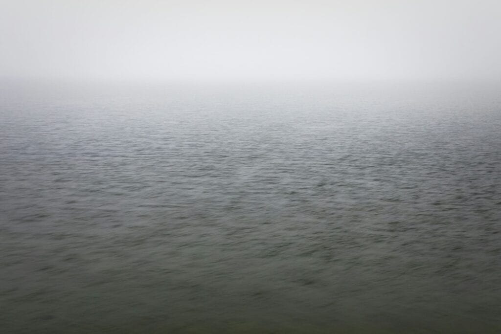Graue Wasserfläche im Nebel als Bild für Trauer bei Krebs.