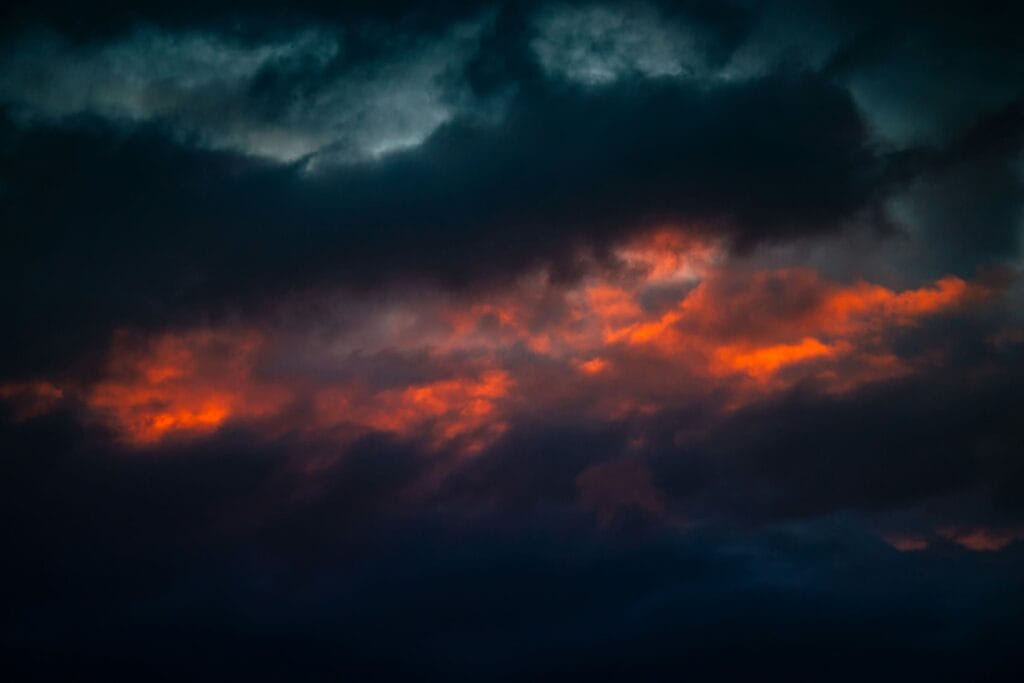 Dunkle Wolken mit roten Lichtstreifen am Himmel als Symbol für Wut nach einer Krebsdiagnose.