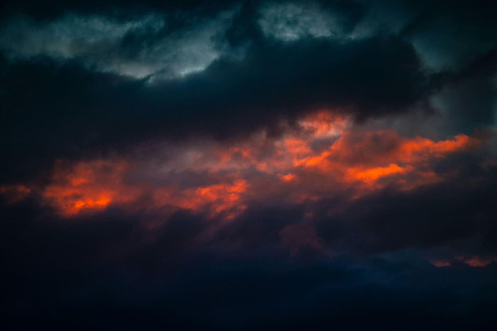 Dunkle Wolken mit roten Lichtstreifen am Himmel als Symbol für Wut nach einer Krebsdiagnose.