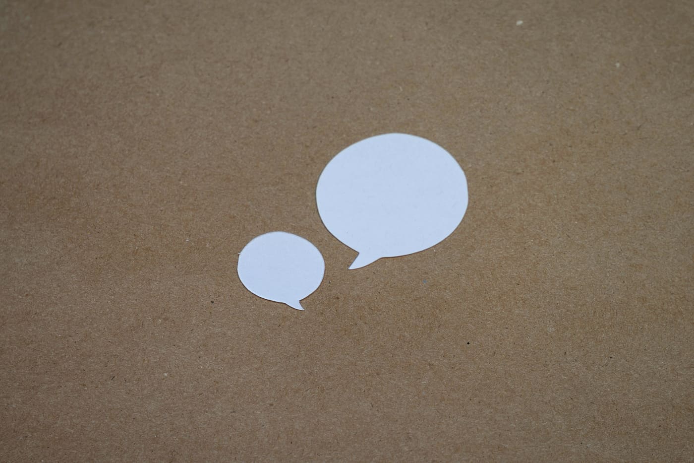 Zwei leere Sprechblasen aus Papier auf braunem Untergrund – Symbol für den Moment, wenn man nicht weiß, wie man eine Krebsdiagnose mitteilen soll