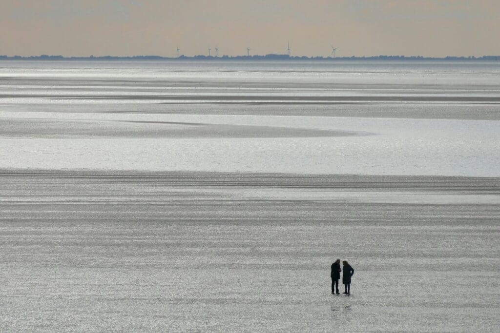 Zwei Menschen stehen zusammen im Wattenmeer – Sinnbild für Nähe und Rückzug bei Krebs